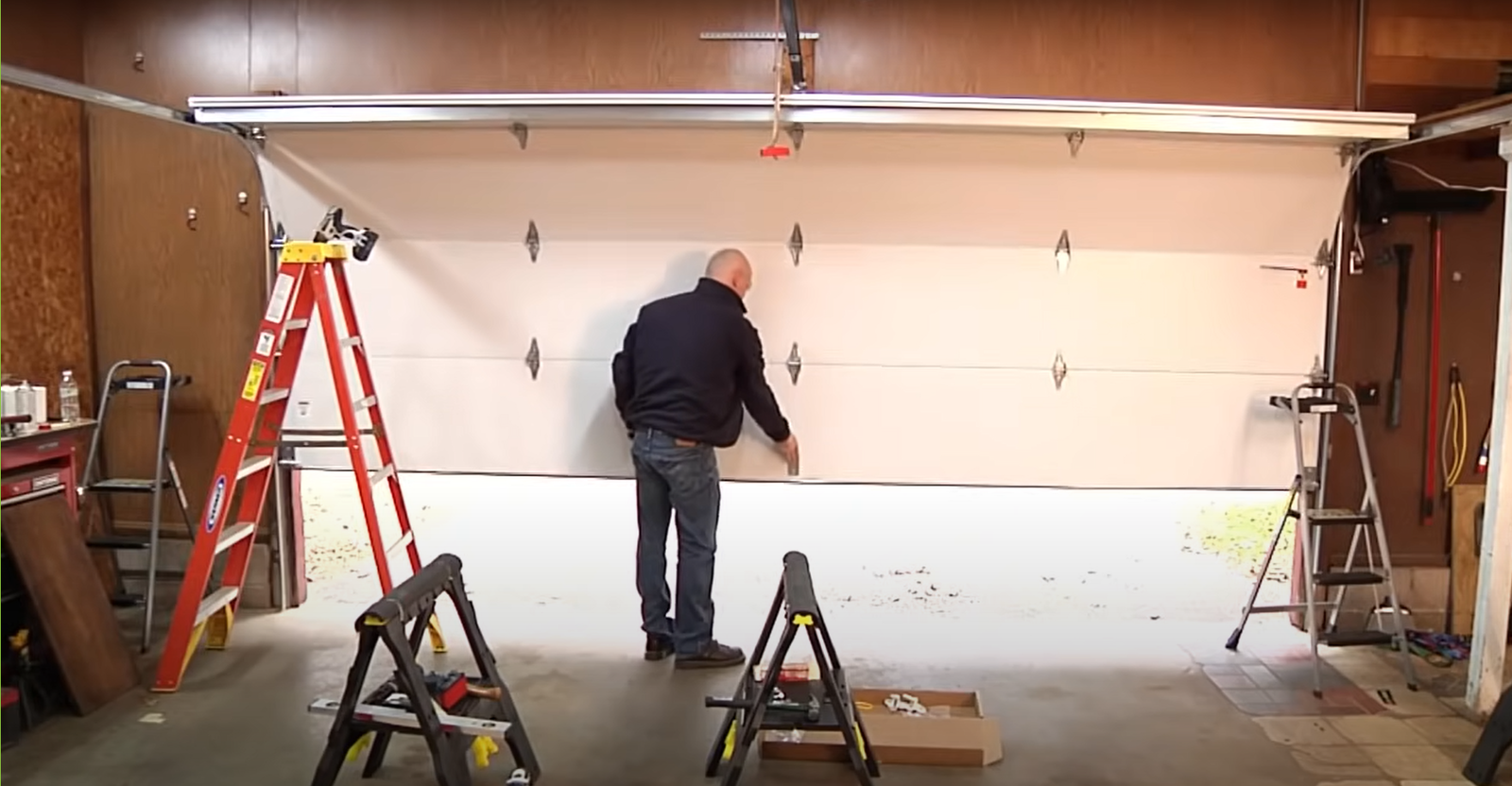 Professional technician installing a sleek black garage door on a suburban home.
