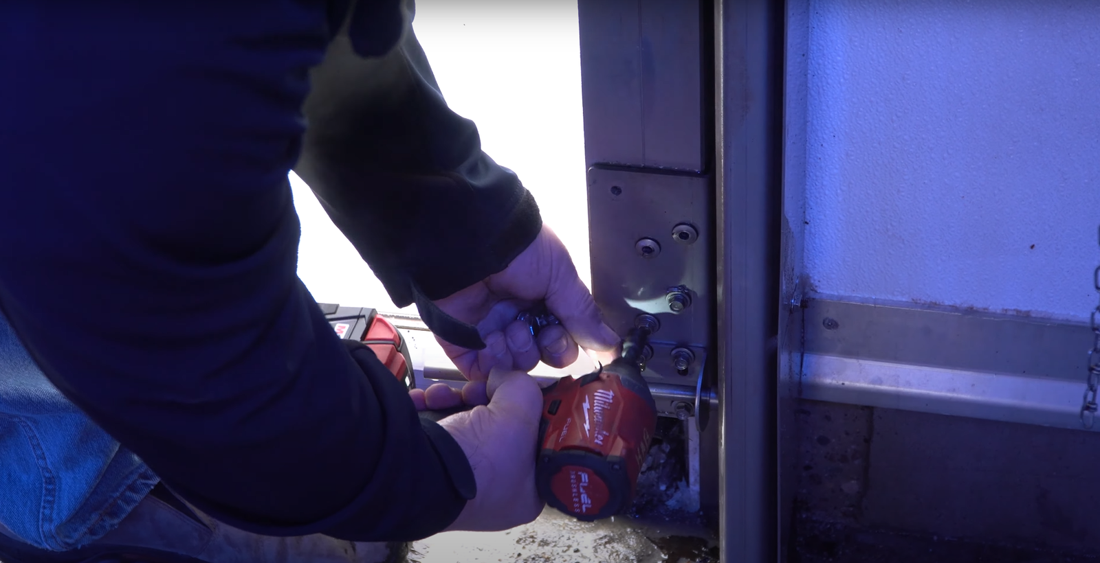 Technician replacing a damaged section of a white garage door, showcasing precise tools and repair work.