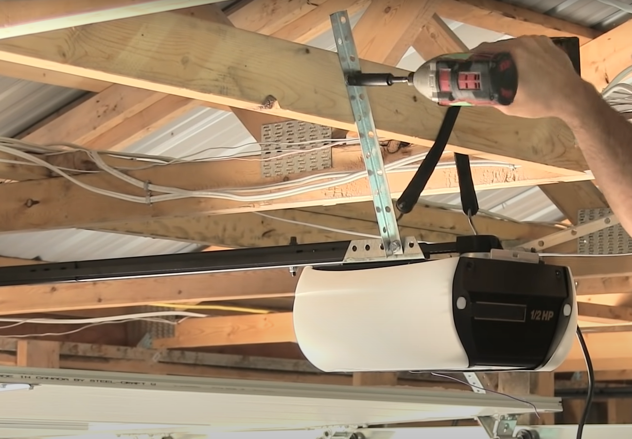 Technician repairing a residential garage door opener mechanism.