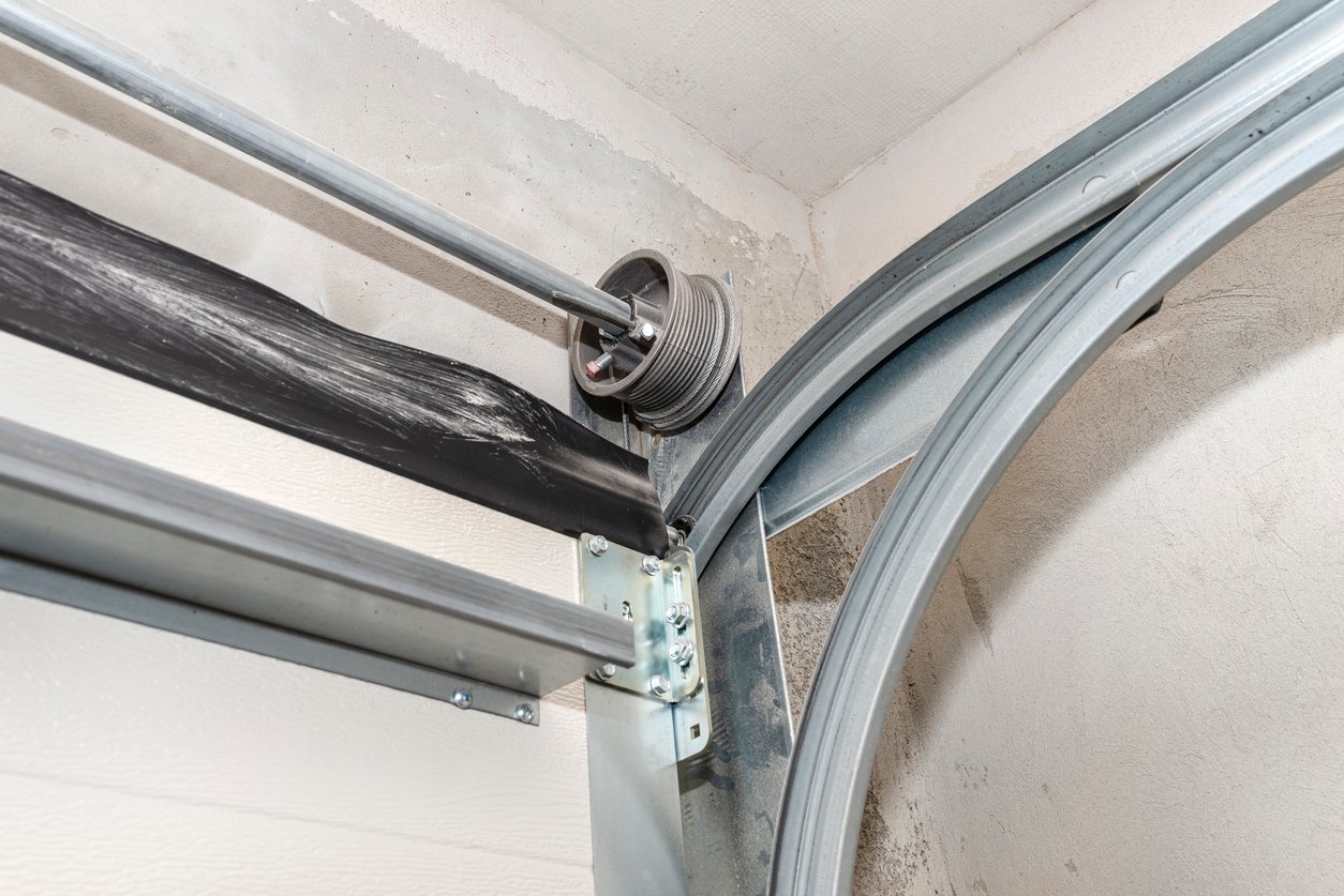 Close-up of a garage door track being tightened with a wrench