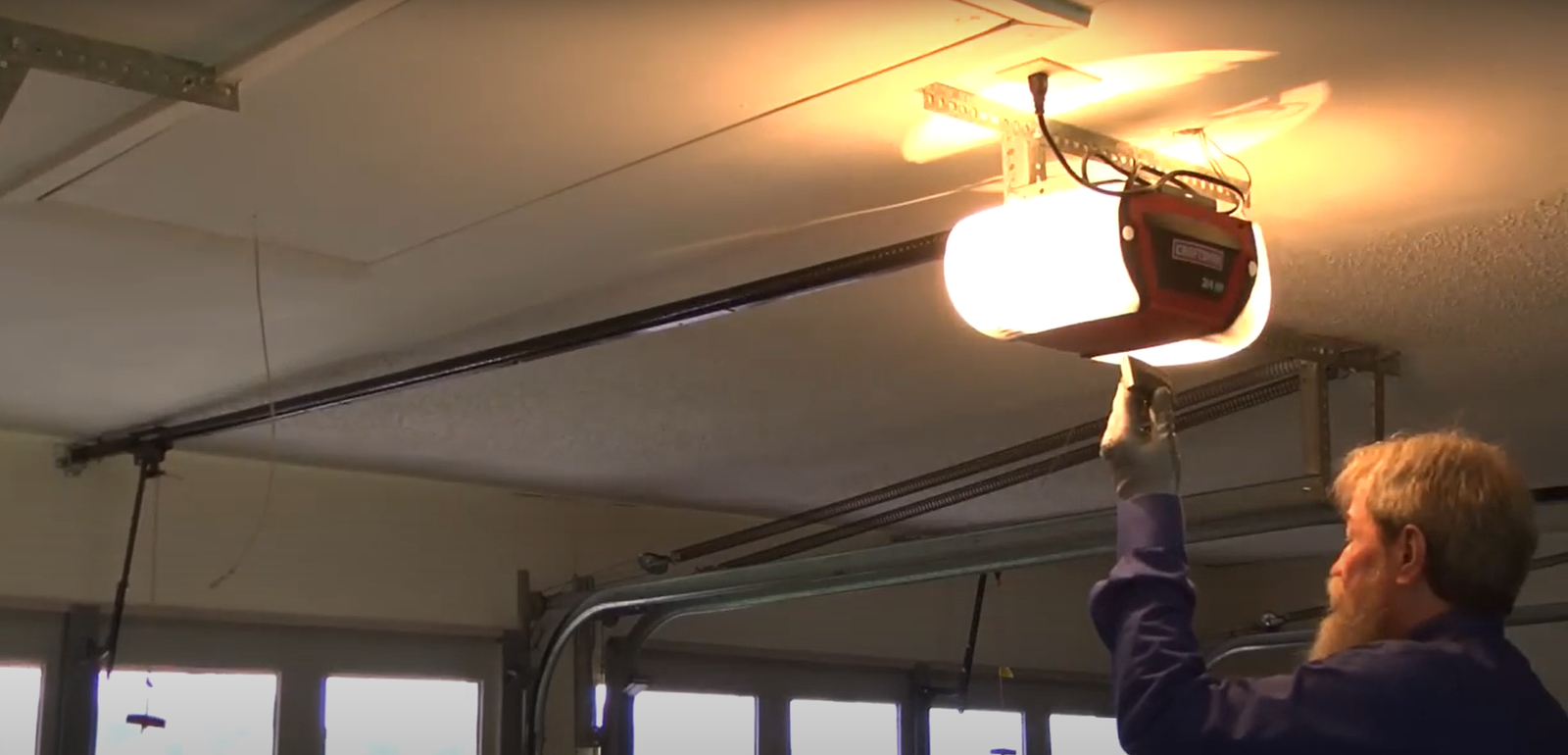 Technician repairing a residential garage door opener mechanism.
