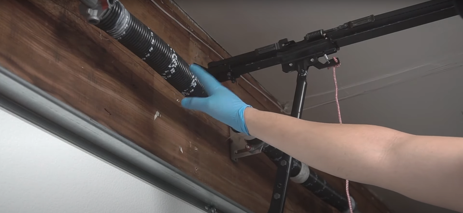 A technician from Hilliard Garage Door Repair inspecting and repairing a garage door spring system.